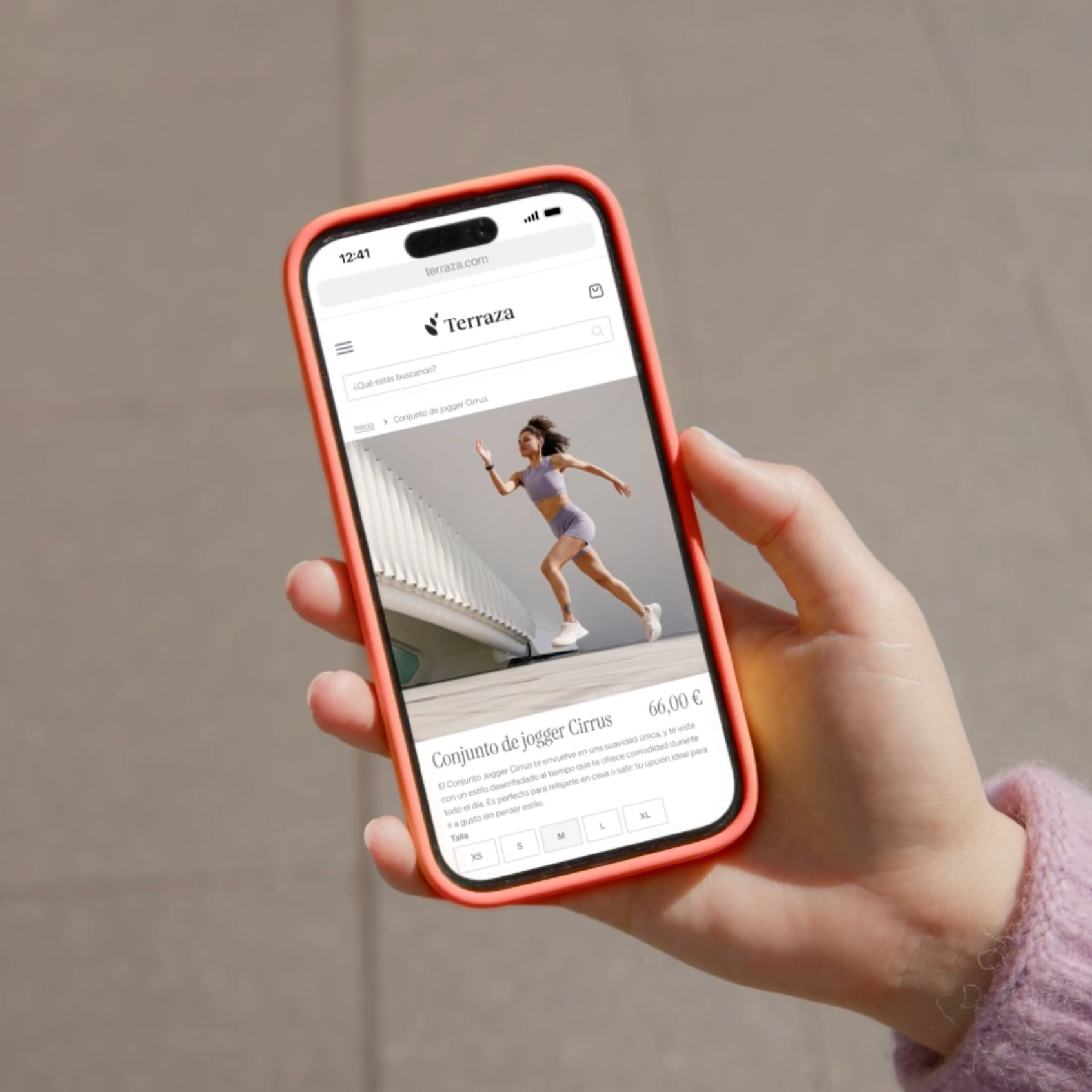 A hand holds a smartphone displaying the Terrazashop website with a woman modeling a purple athletic set.