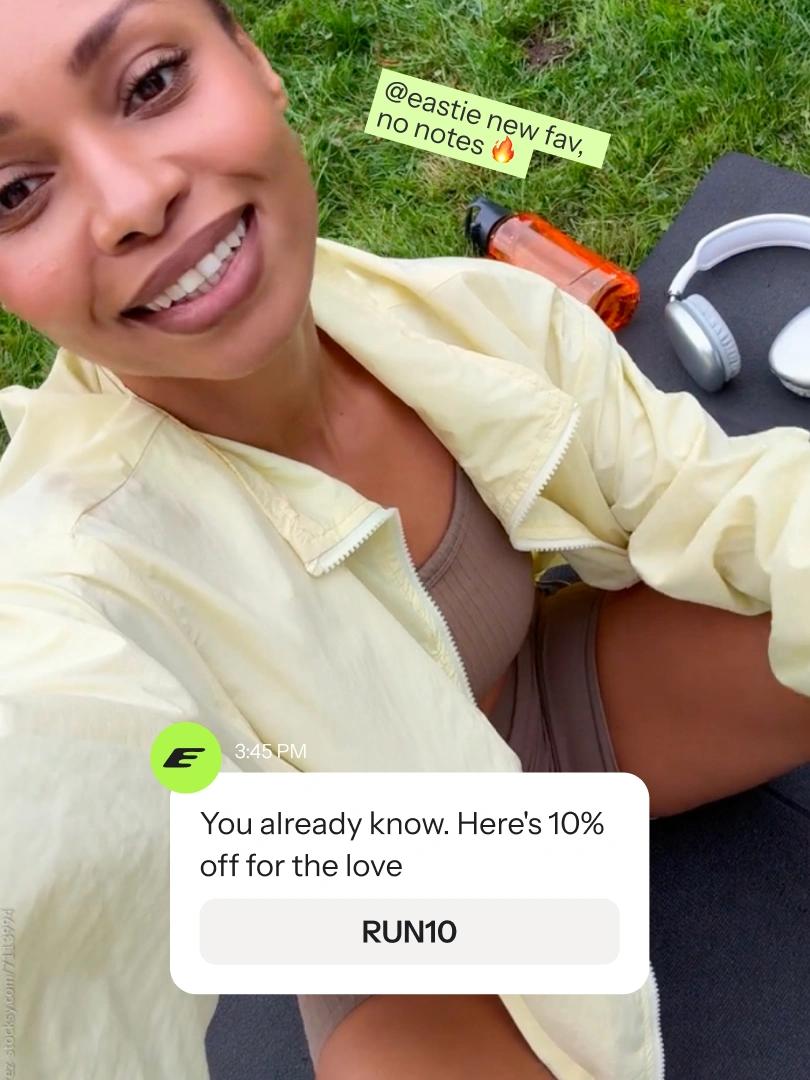 Smiling woman takes a selfie on grass beside headphones and a water bottle, with a 10% off promo overlay.