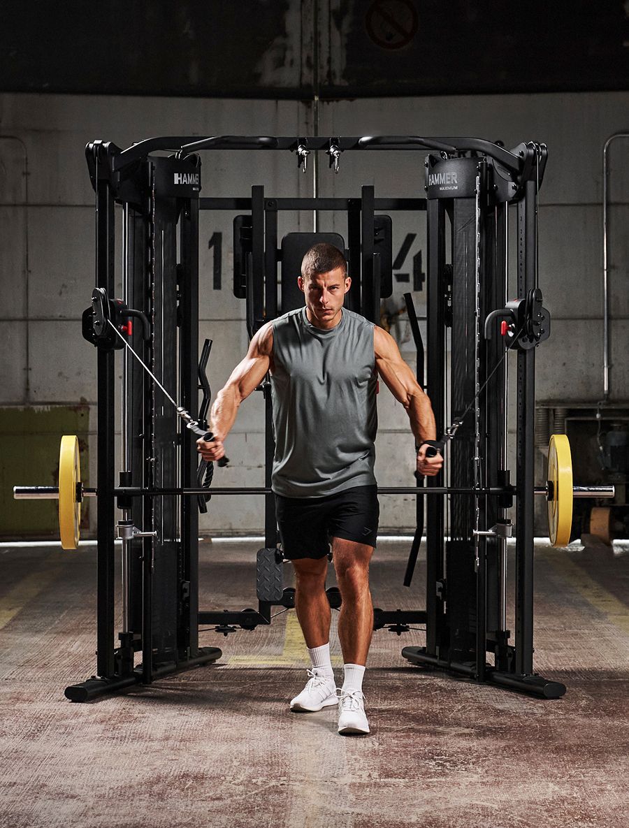 A muscular man performing cable crossovers on a HAMMER multi-gym.