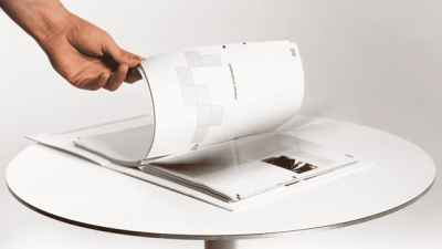 Speeches That Changed the World publication design – interior spread with typographic grid layout, hand flipping page on white table