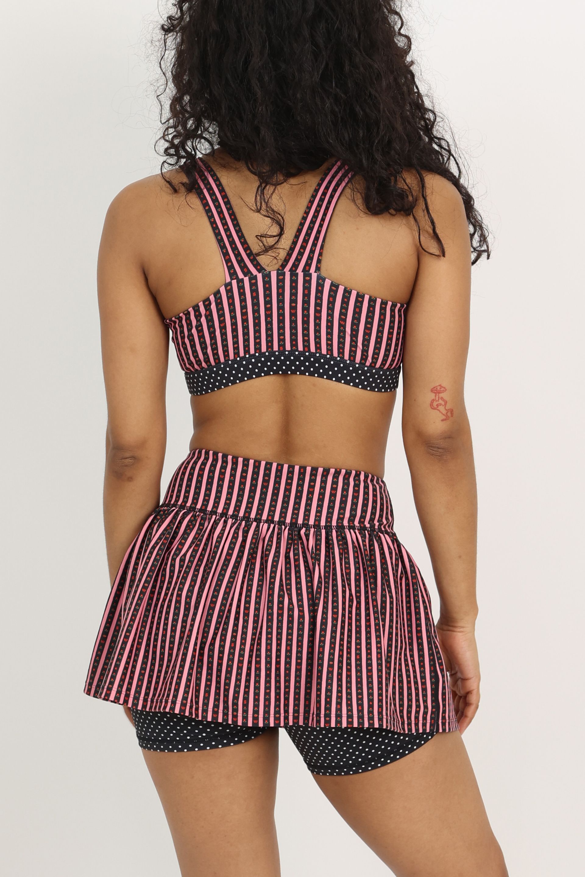 Gathered ruffle exercise skort in a hand-drawn, Pink/Black floral border stripe print with contrast black and white polka dot print and gingham bow details.