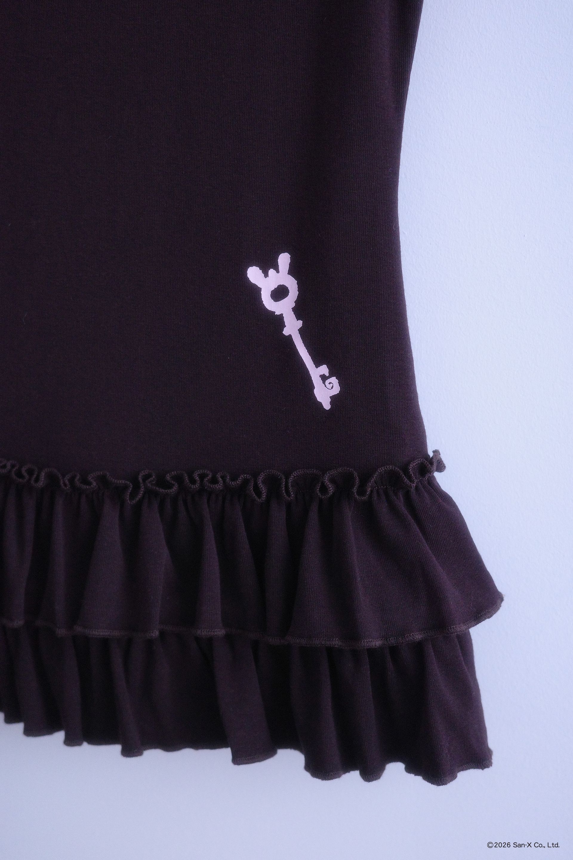 Close up flat image the back of the Sweets top. Short sleeve, brown, ruffle hem top with a screenprinted baby pink key on the bottom right.