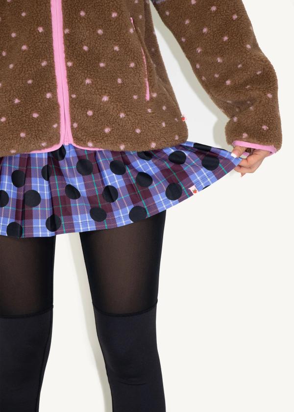 Closeup of model wearing a pleated school girl skirt in a plaid polka dot print with attached interior legging.