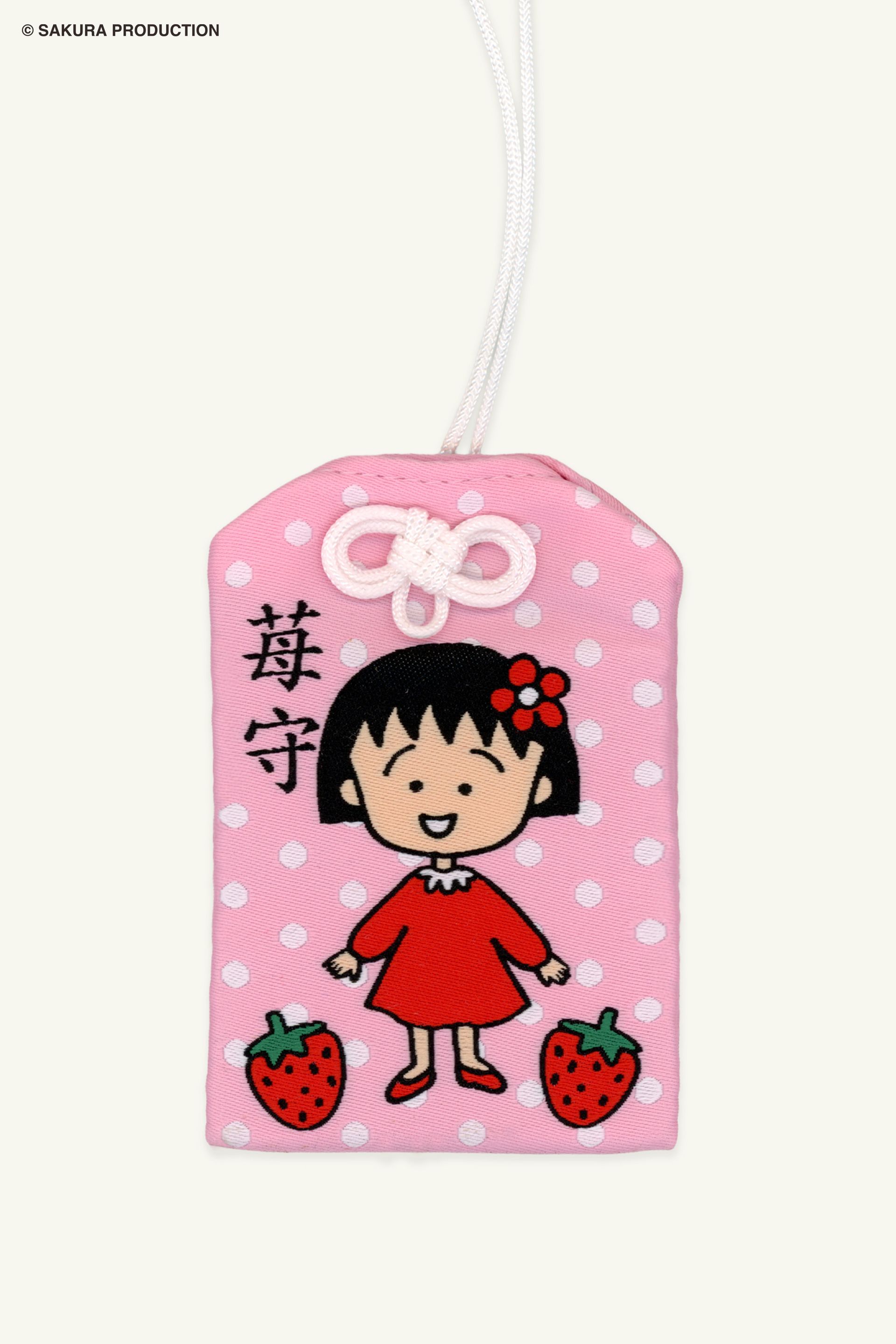 Flat image of Chibi Maruko Chan Omamori Keychain. Pink omamori charm with white polka dots, Chibi Maruko-chan in a red dress, and two strawberries. In Japanese in reads "Strawberry Protection." 