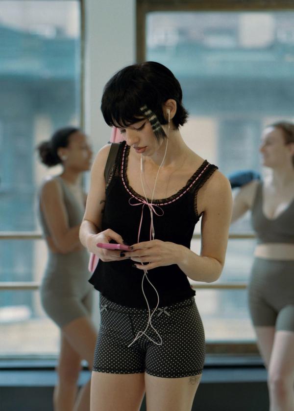 Emo girl leaving yoga class with headphones in wearing black waffle knit tank with lace and ribbon trim and polka dot yoga shorts with gingham bows.