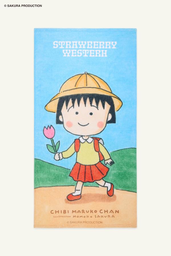 Flat image of towel. Hand drawn image of young Chibi Maruko Chan holding a pink tulip against a natural backdrop. Top of towel reads Strawberry Western in white. Bottom of towel reads "Chibi Maruko Chan, illustration Momoko Sakura, Sakura Production."