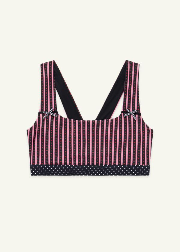 Front of wide strap sports bra in a hand-drawn, pink and black floral border stripe print with contrast black and white polka dot print elastic band and gingham bow details.