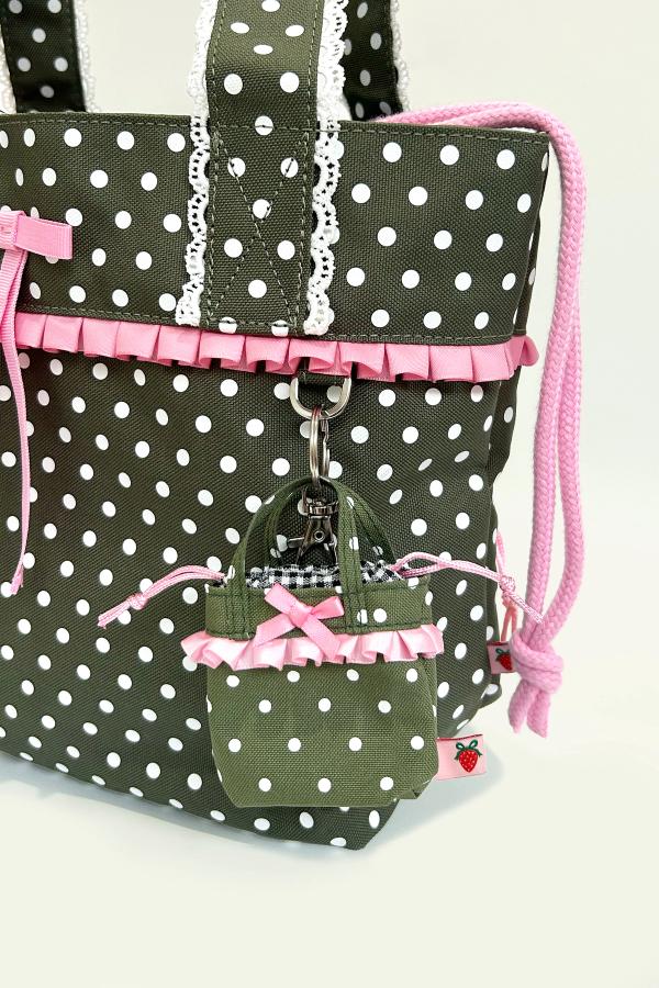 Mini Ichigo Bag Keychain in Olive green with white polka dots, black and white gingham lining, baby pink bow and ruffle trim attached to big Ichigo Bag with a keyring.