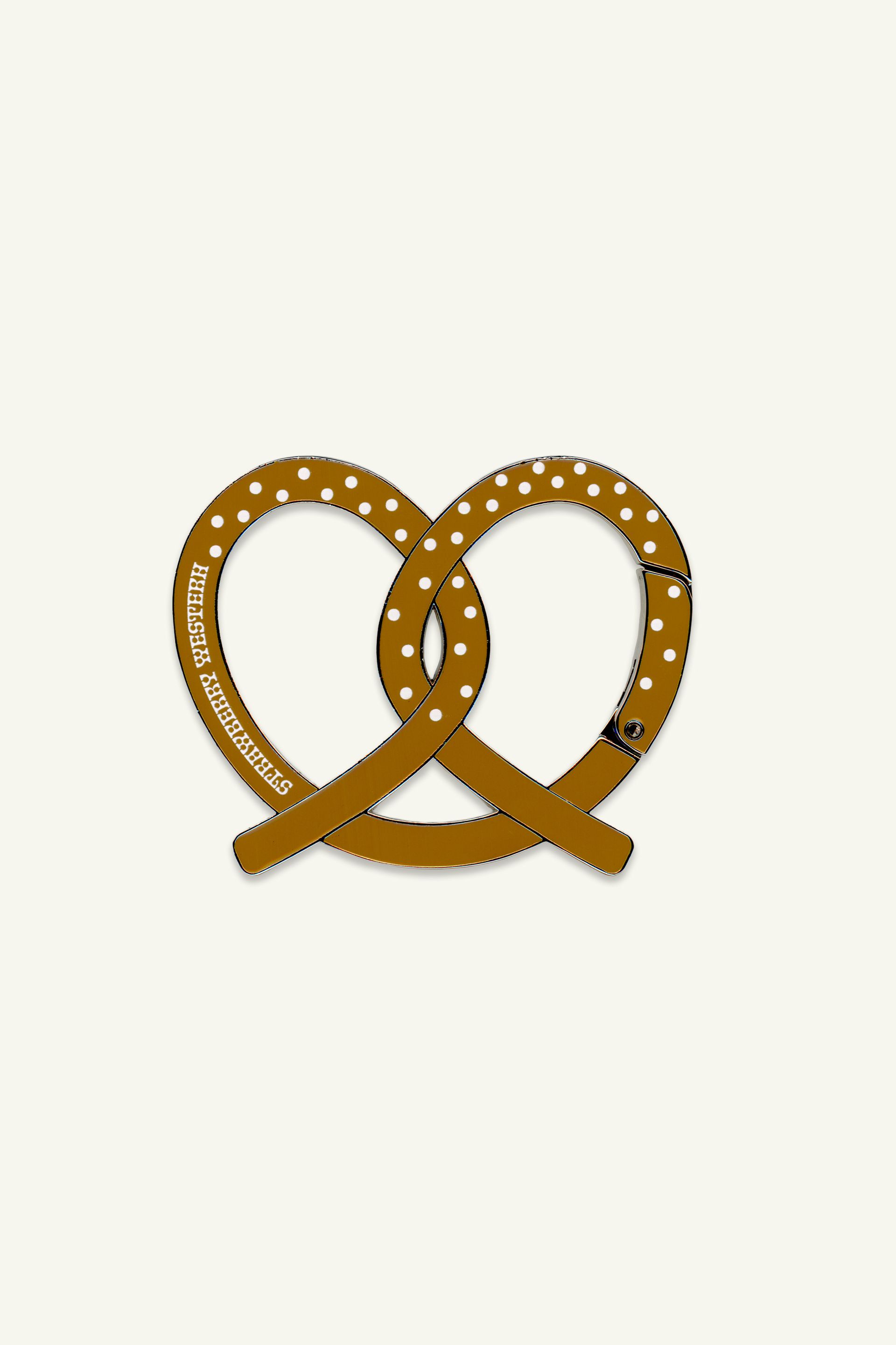Classic NY Pretzel shaped carabiner keychain clip. Made from Zinc Alloy with enamel fill and printed polka dots and Strawberry Western logo.