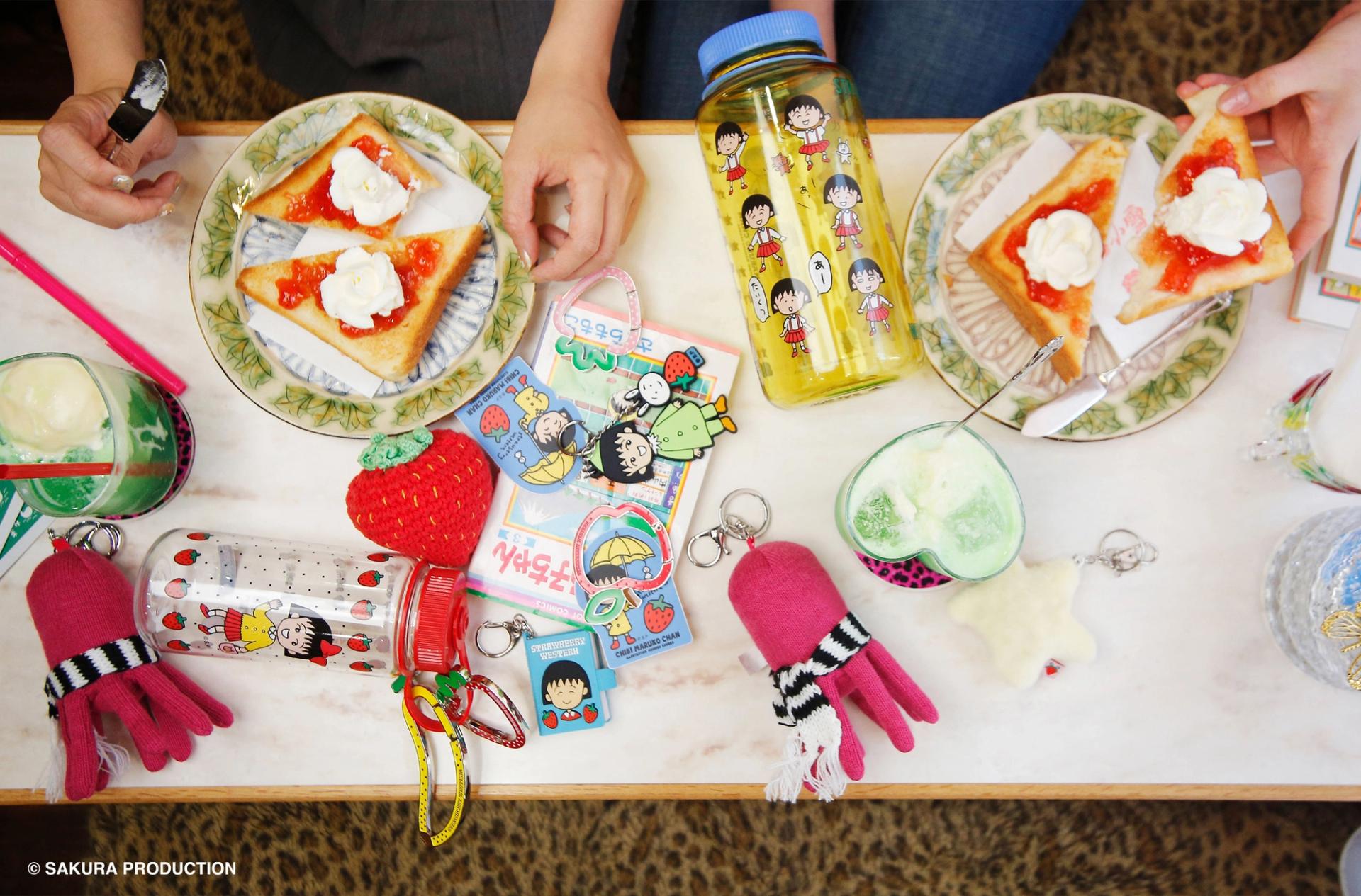 Table featuring various accessories, manga, drinks and two plates of french toast.