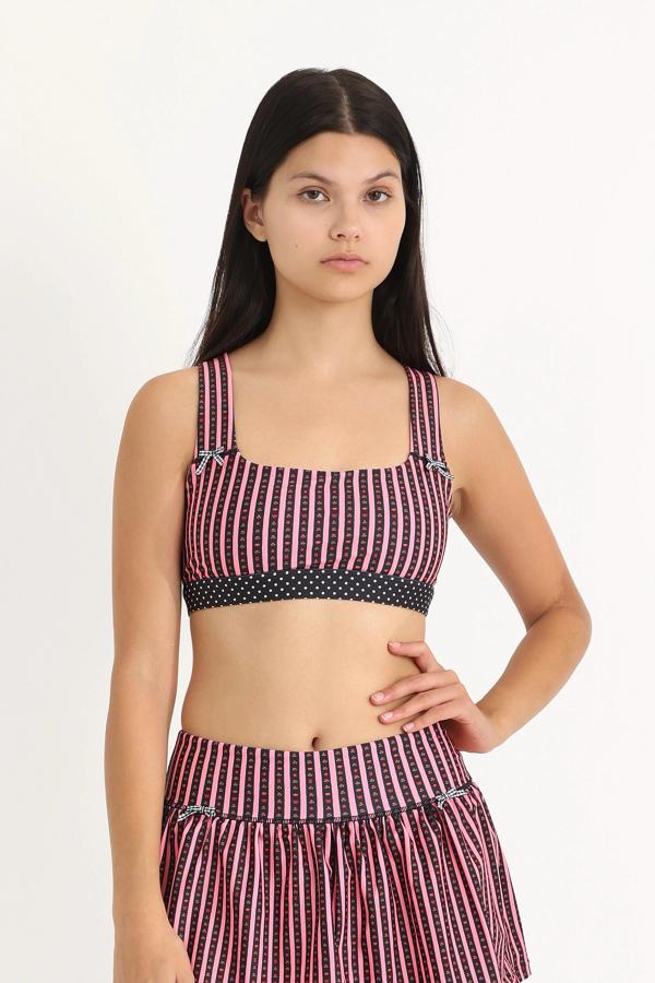Front view of medium-support Coco Sports Bra silhouette featuring a hand-drawn, floral border stripe print in Pink/Black with contrast polka dot print elastic band and gingham bow details.