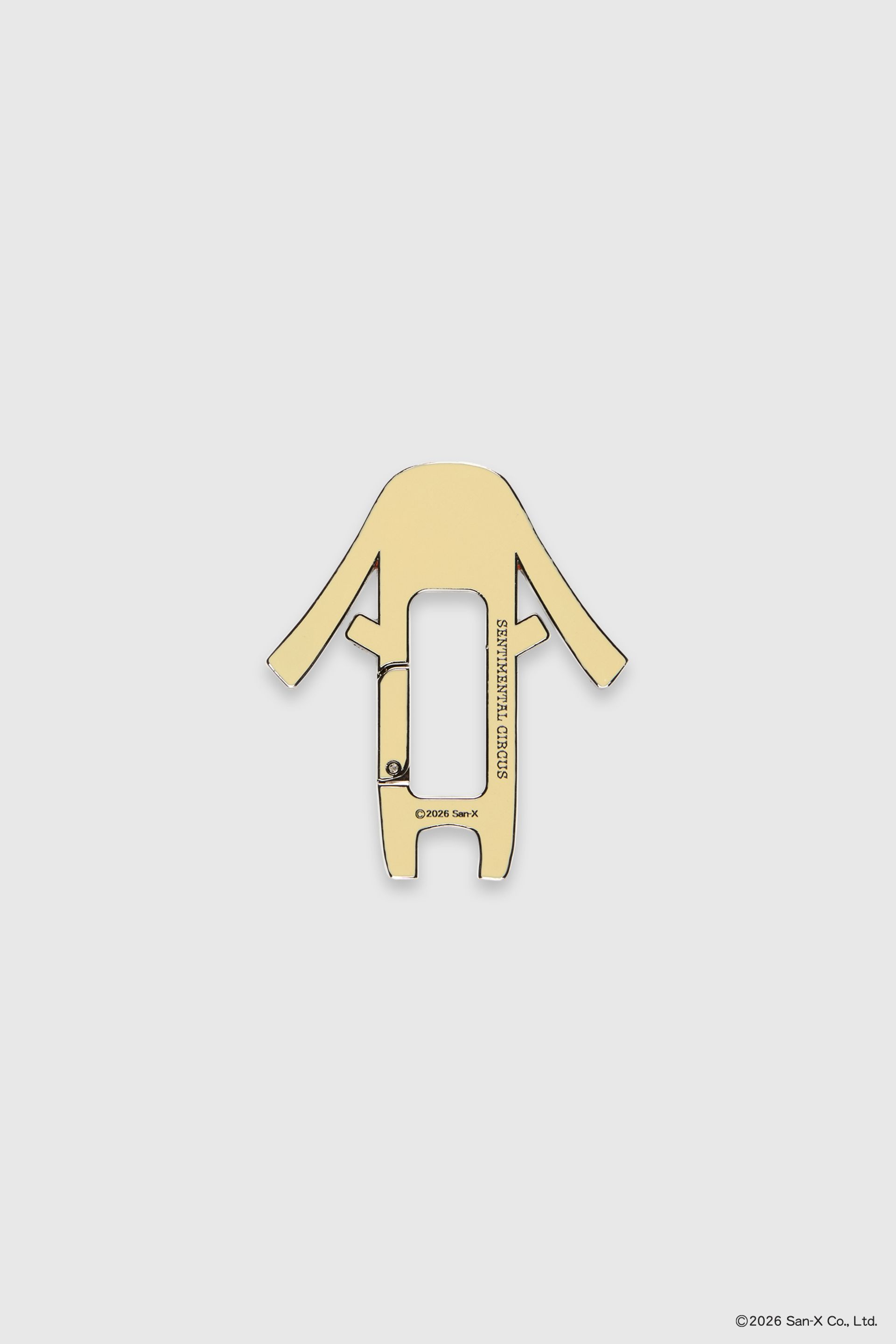 Flat image of back of Toto carabiner, shaped like a dog/bunny hybrid with long, floppy ears. The skin color is yellow. Sentimental Circus logo on back.