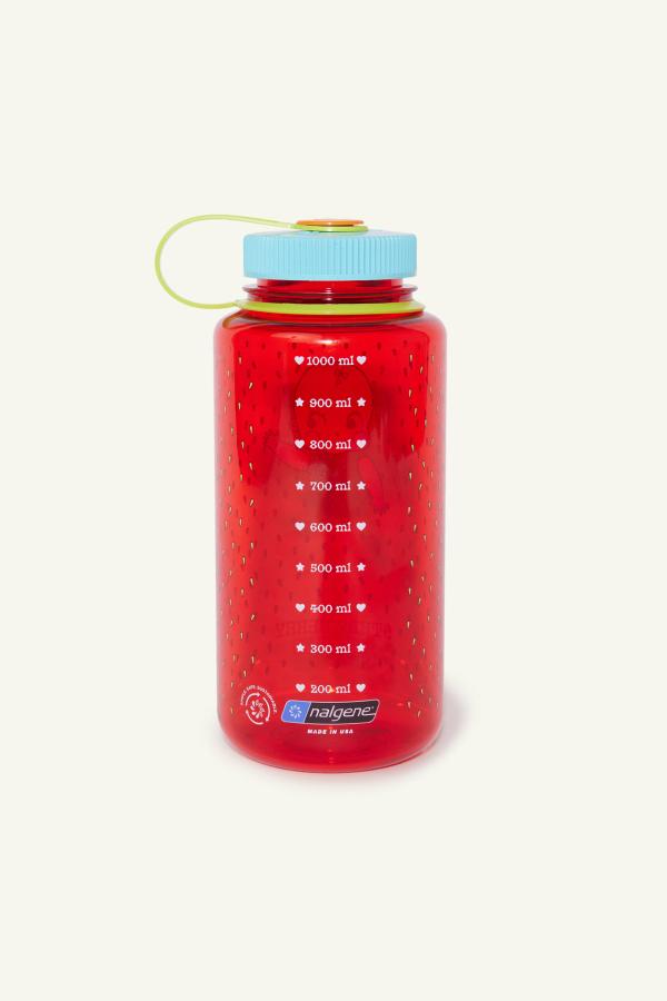 Back of red water bottle with blue cap, green strap, and printed liquid measurement chart.