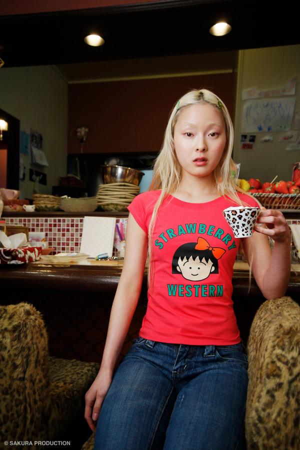 Girl sitting in a Japanese cafe, holding a leopard print tea cup. She wears the Hot Pink Chibi Maruko Chan Raglan Top.