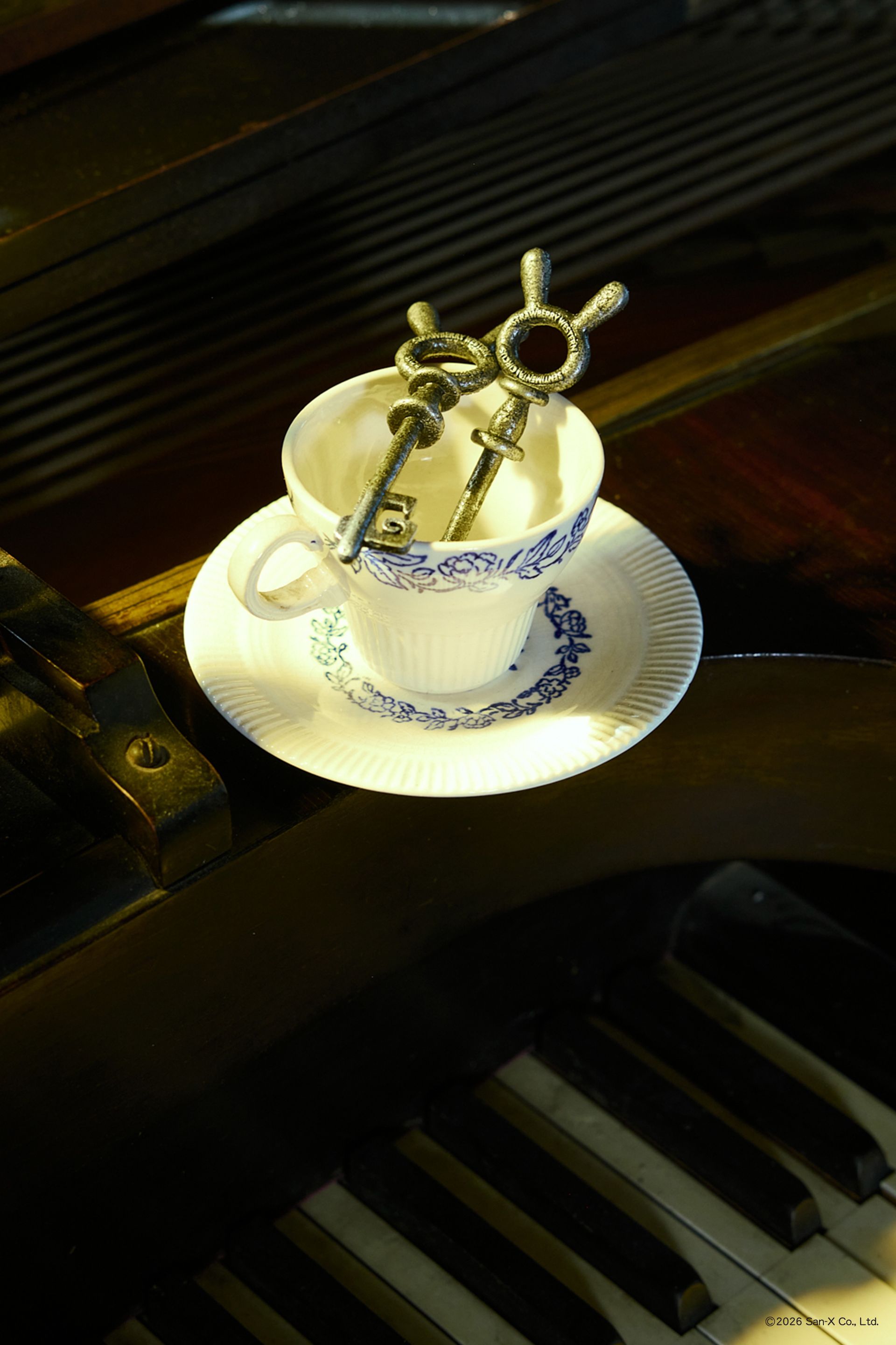 Image of a teacup set holding a pair of two beautiful and heavy Sentimental Circus skeleton keys on a large hinged, jailer ring. These bunny head keys were brought to life from 2D in a cast iron texture featuring the Sentimental Circus and Strawberry Western logos on both sides. 