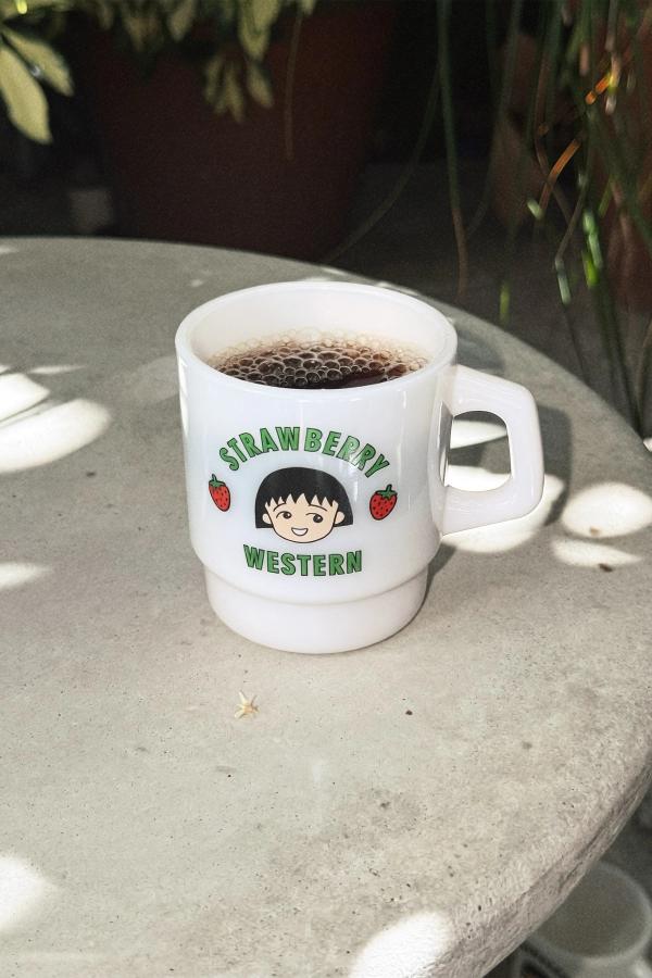 Cloud Chibi Maruko Chan Milky Mug filled with coffee. The front reads Strawberry Western in green lettering. In the middle is Chibi Maruko-chan's face surrounded by two strawberries.