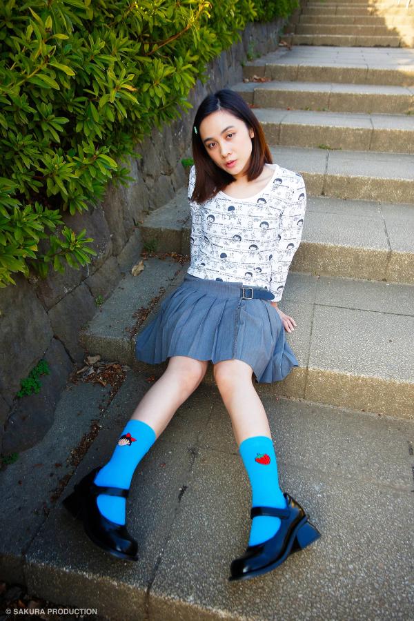 Image of a girl wearing the blue sock sitting on concrete steps.