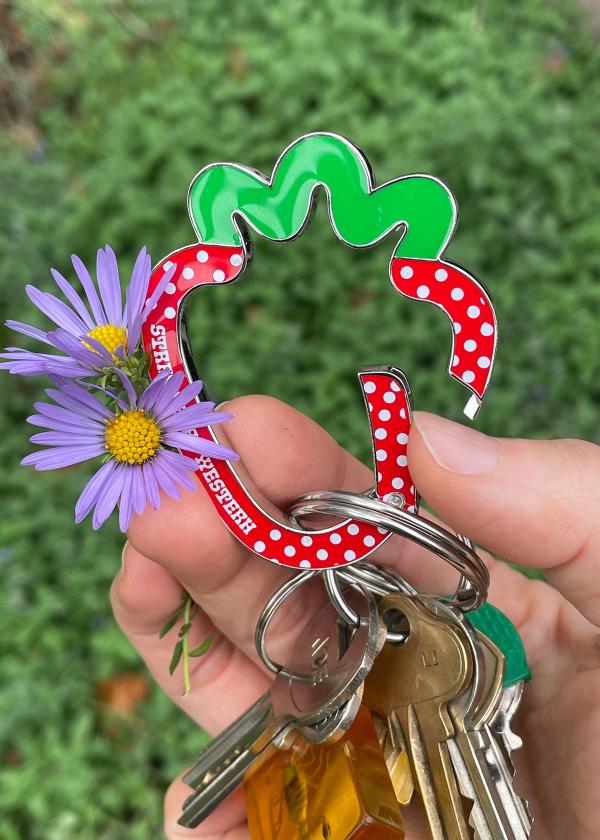 Hand holding a set of keys on a strawberry shaped metal carabiner.