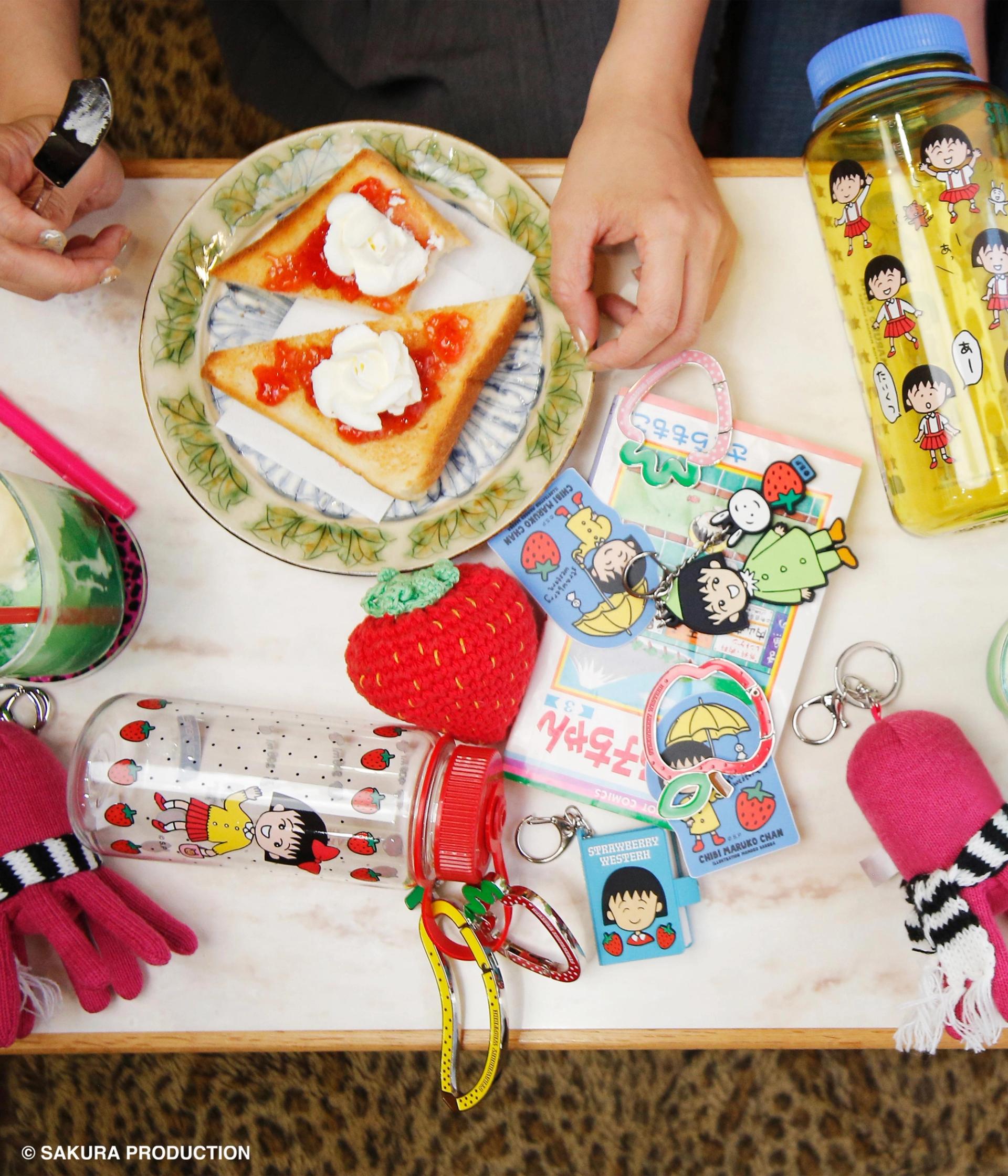 Table featuring various accessories, manga, drinks and two plates of french toast.