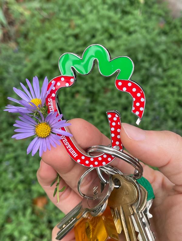 Hand holding a set of keys on a strawberry shaped metal carabiner.