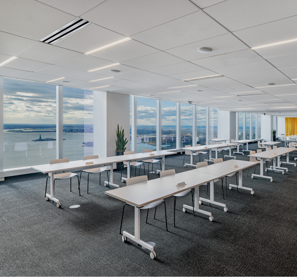 A spacious open conference or event space with rows of tables and chairs. One of Well& by Durst's offerings at One World Trade Center.
