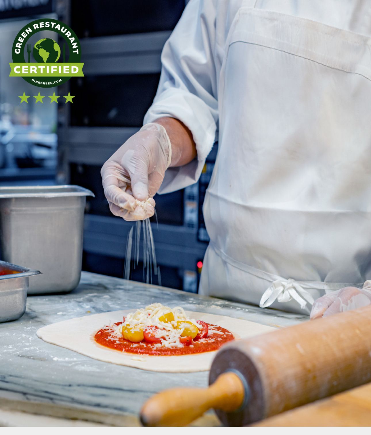 Pizza chef flattening dough on a kitchen surface.