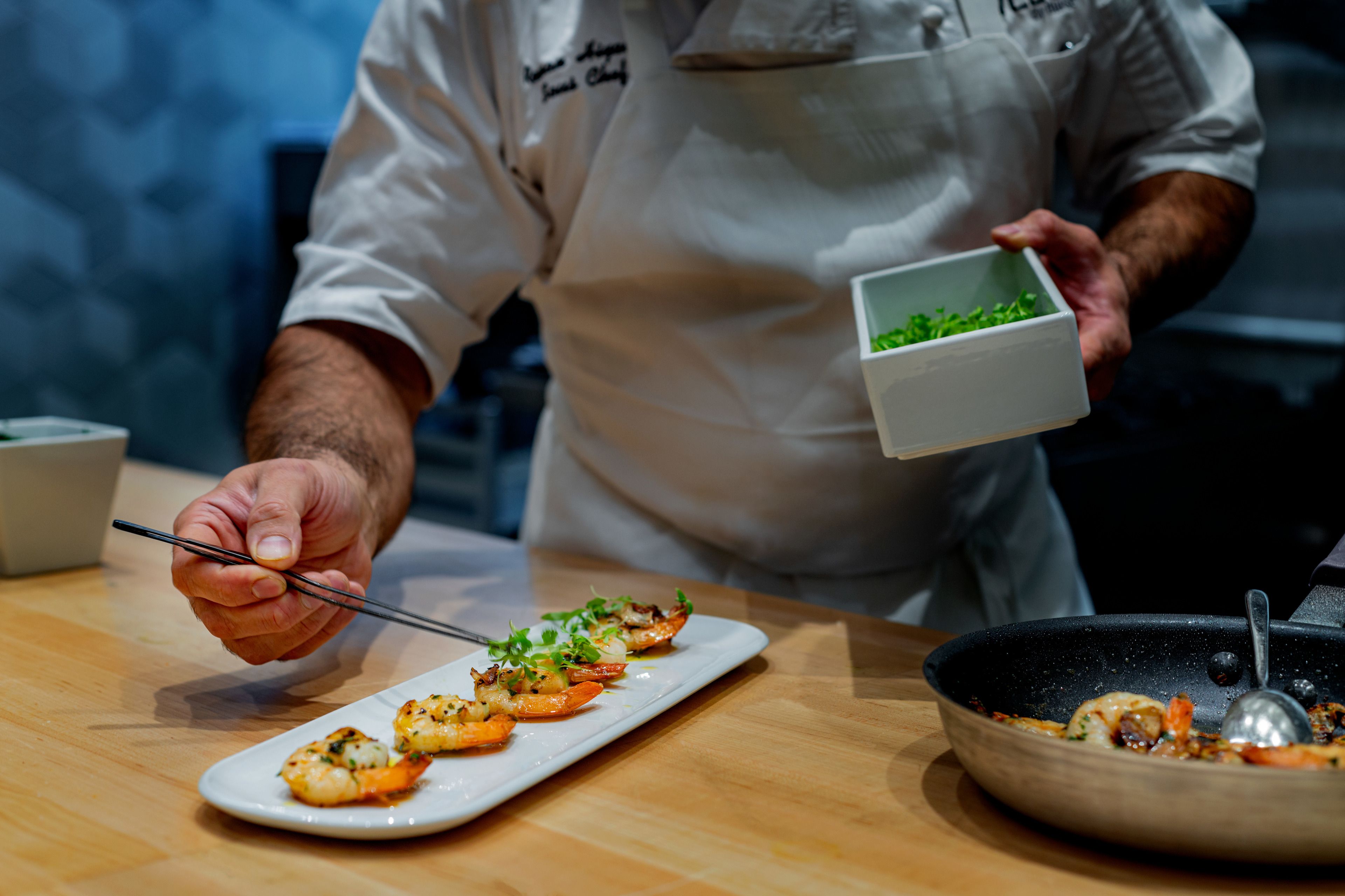 Skilled sous chef arranging shrimp artistically on a plate