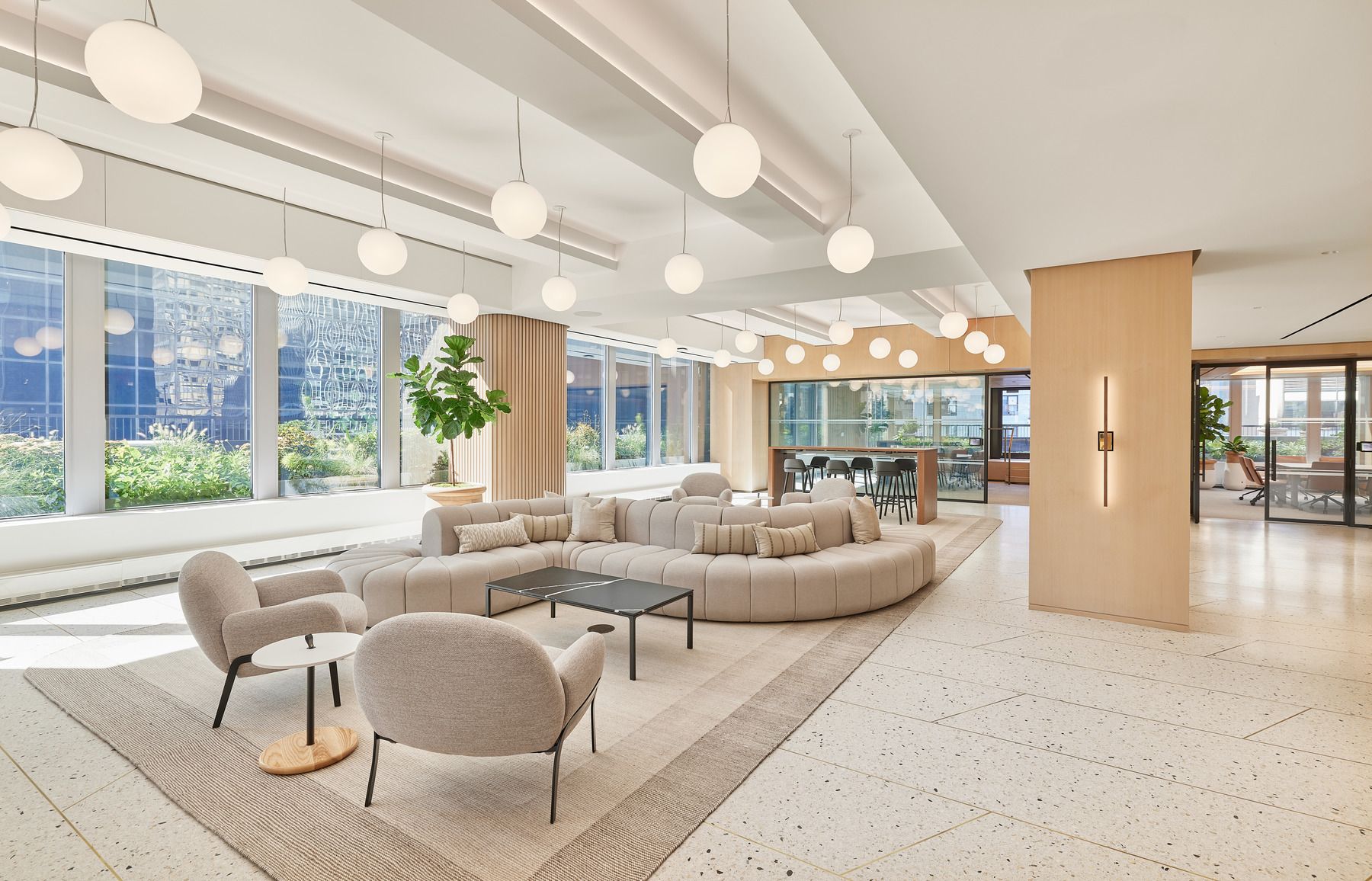 A brightly lit chic conference room with natural light from floor to ceiling windows filled with modern looking furniture.