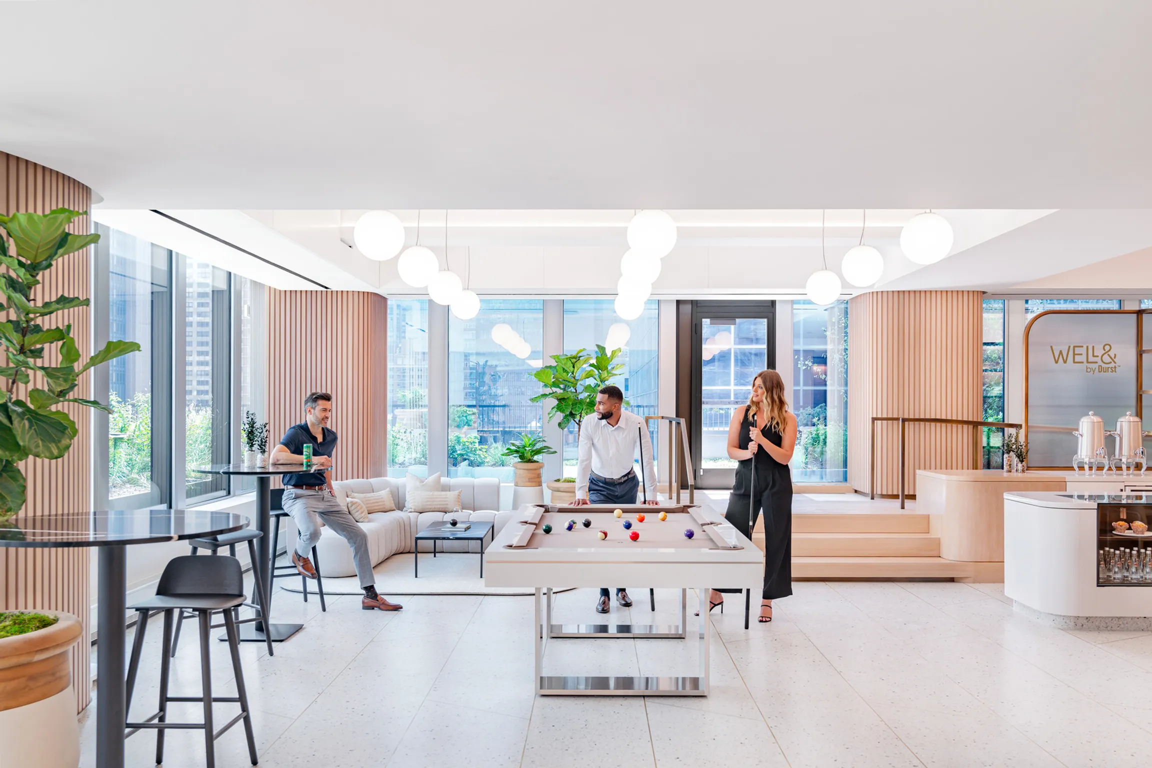Multicultural individuals standing around a pool table on the 825 Third Avenue amenity floor, participating in an engaging conversation