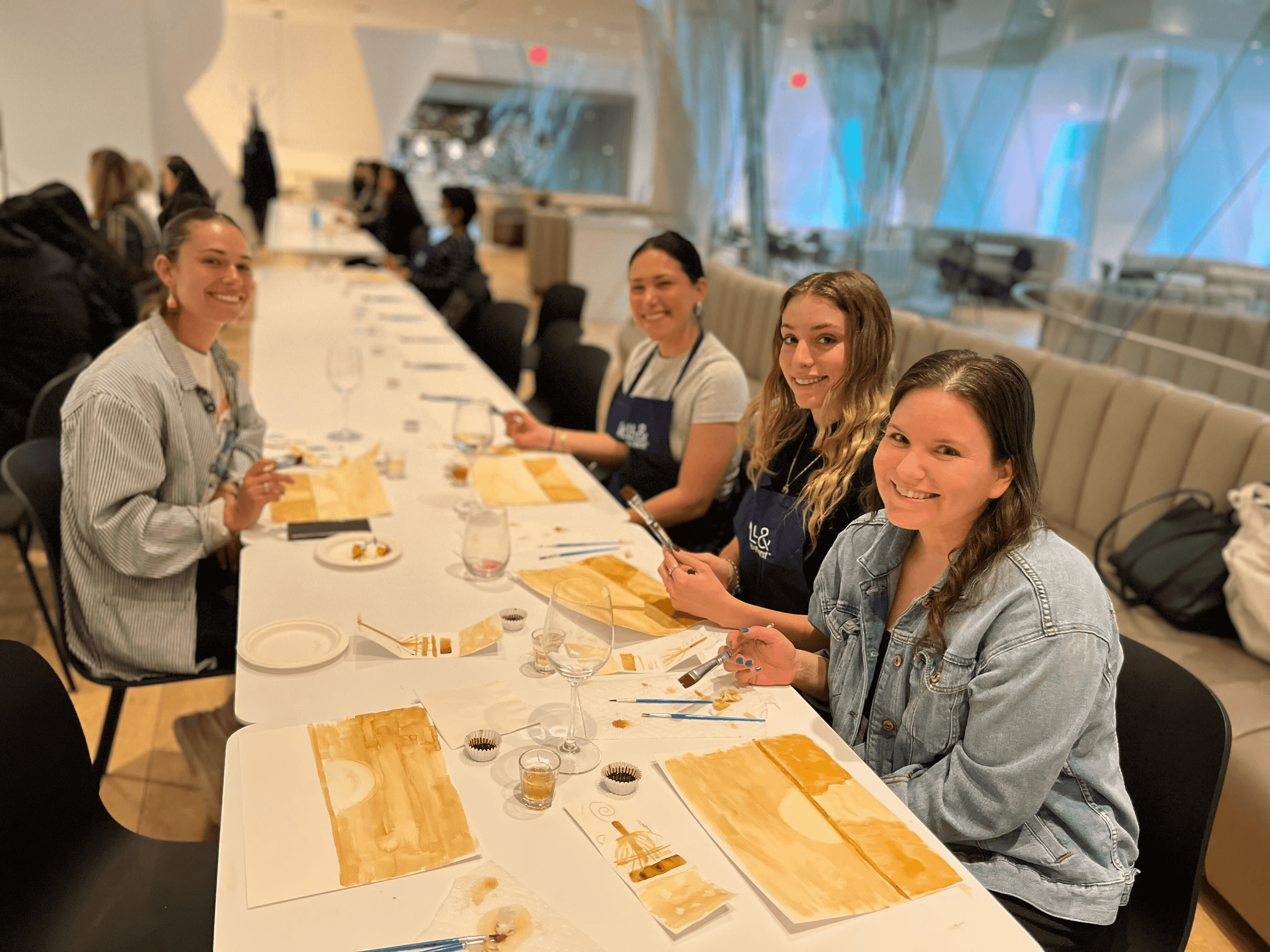 Women gathered around the table at a painting class in Well& by Durst's event space.