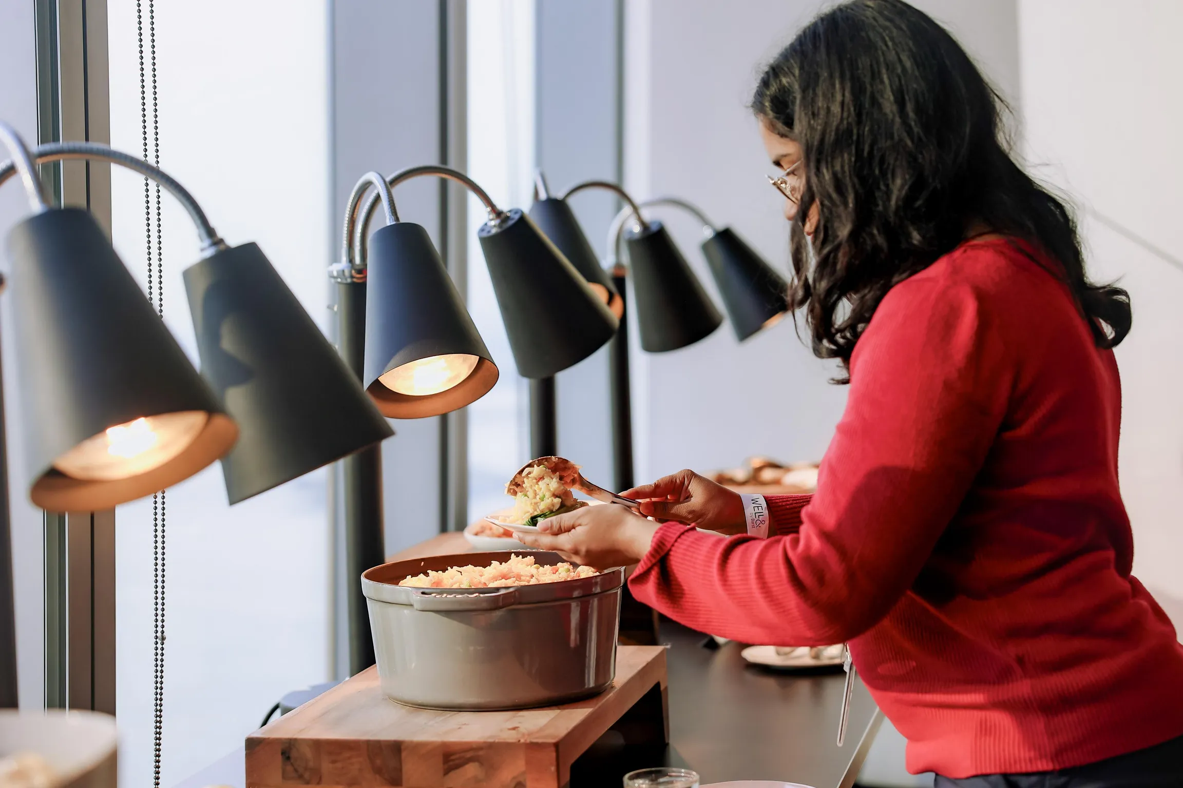 Young woman spooning out food at buffet at an event at Well& at One World Trade Center