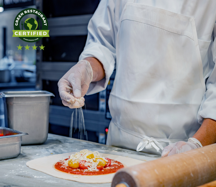 Pizza chef flattening dough on a kitchen surface.