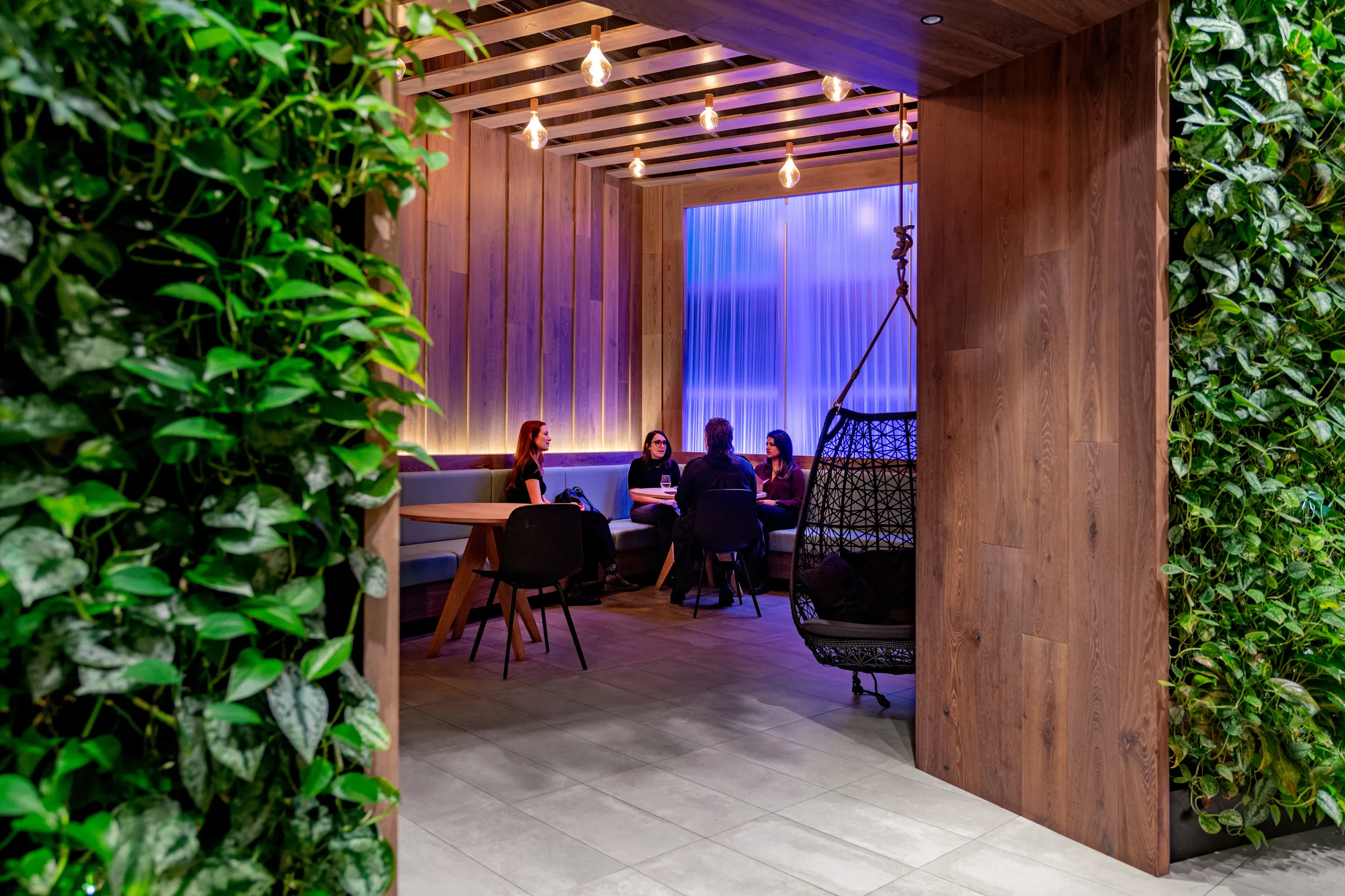 Four young women chatting in the Treehouse area, adjacent to The Green