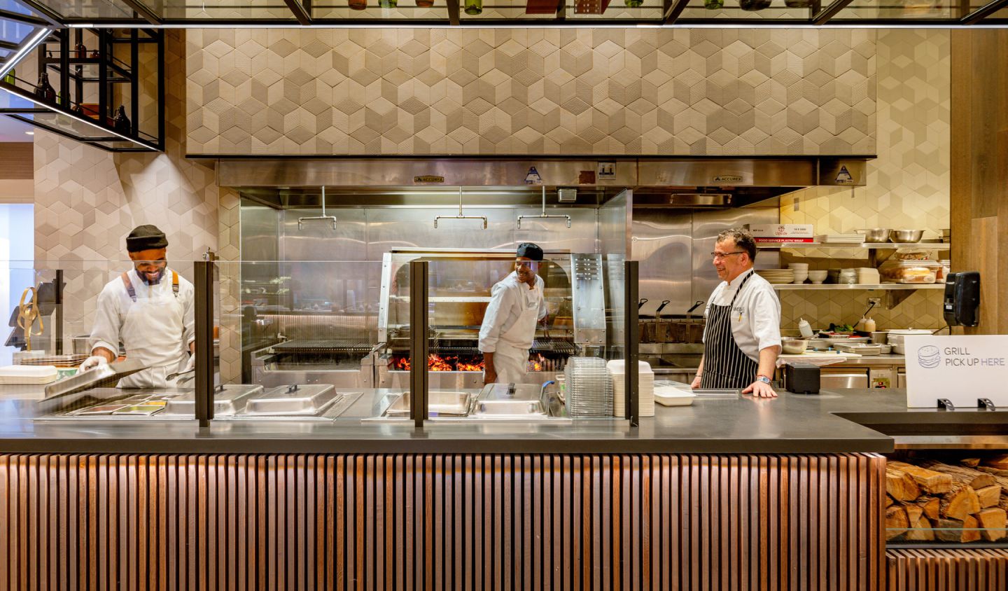 Professional chefs collaborating in Well& by Durst's restaurant kitchen, preparing delicious dishes for customers.