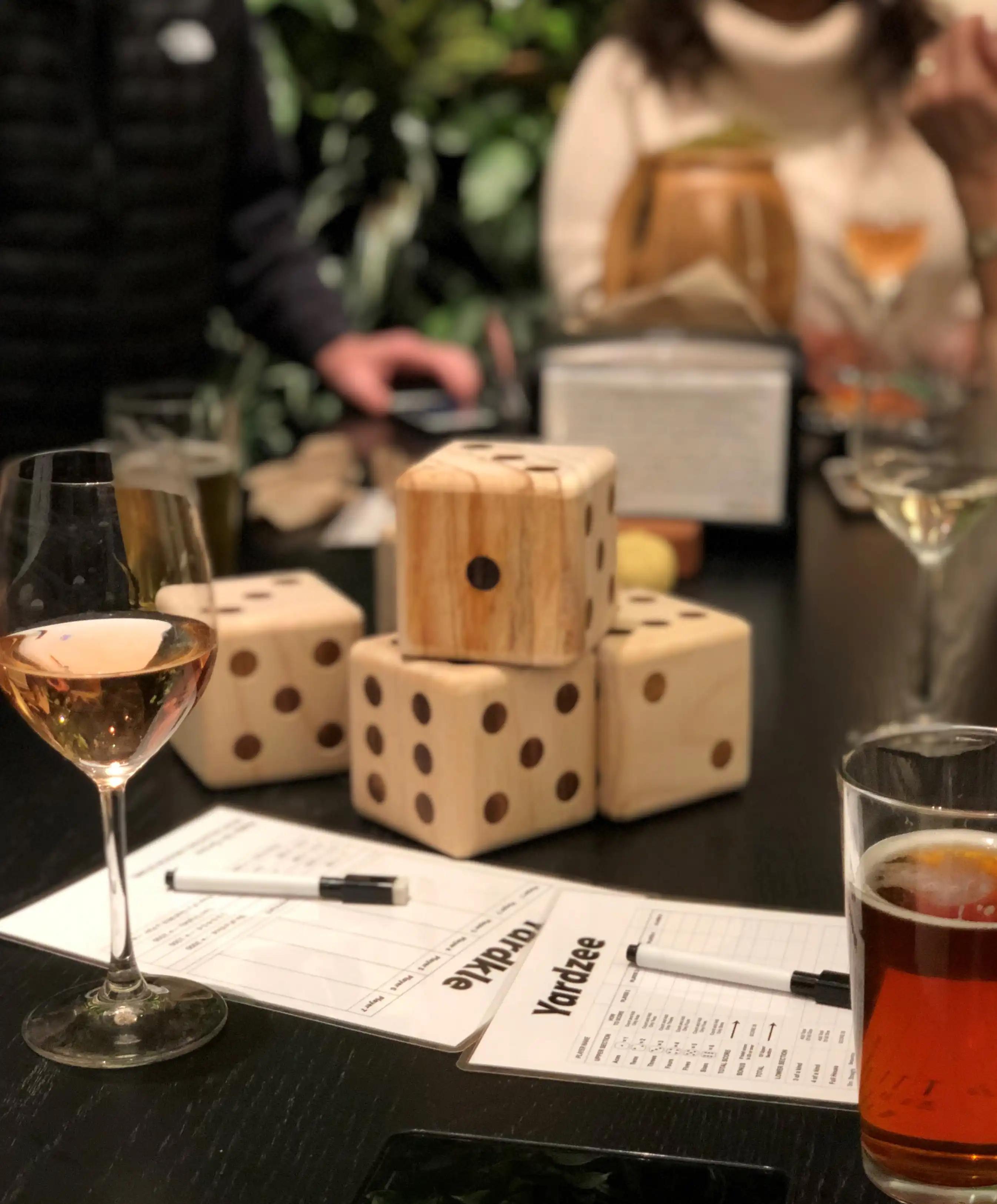 A table with wooden dice, sheets of paper, a glass of wine and a glass of beer.