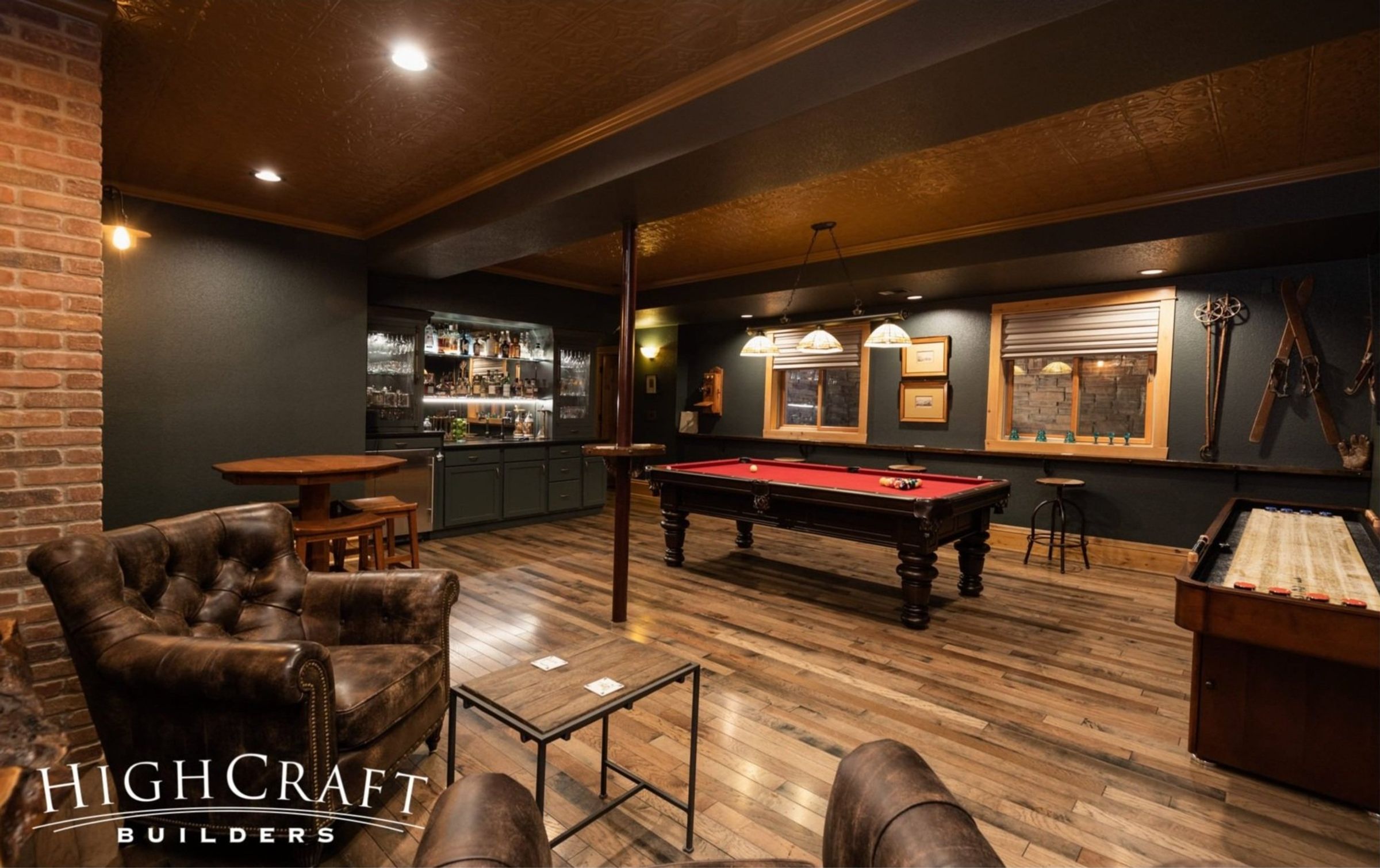 Photo of cozy basement speakeasy. Black walls, dark wood, and exposed brick create a moody atmosphere.