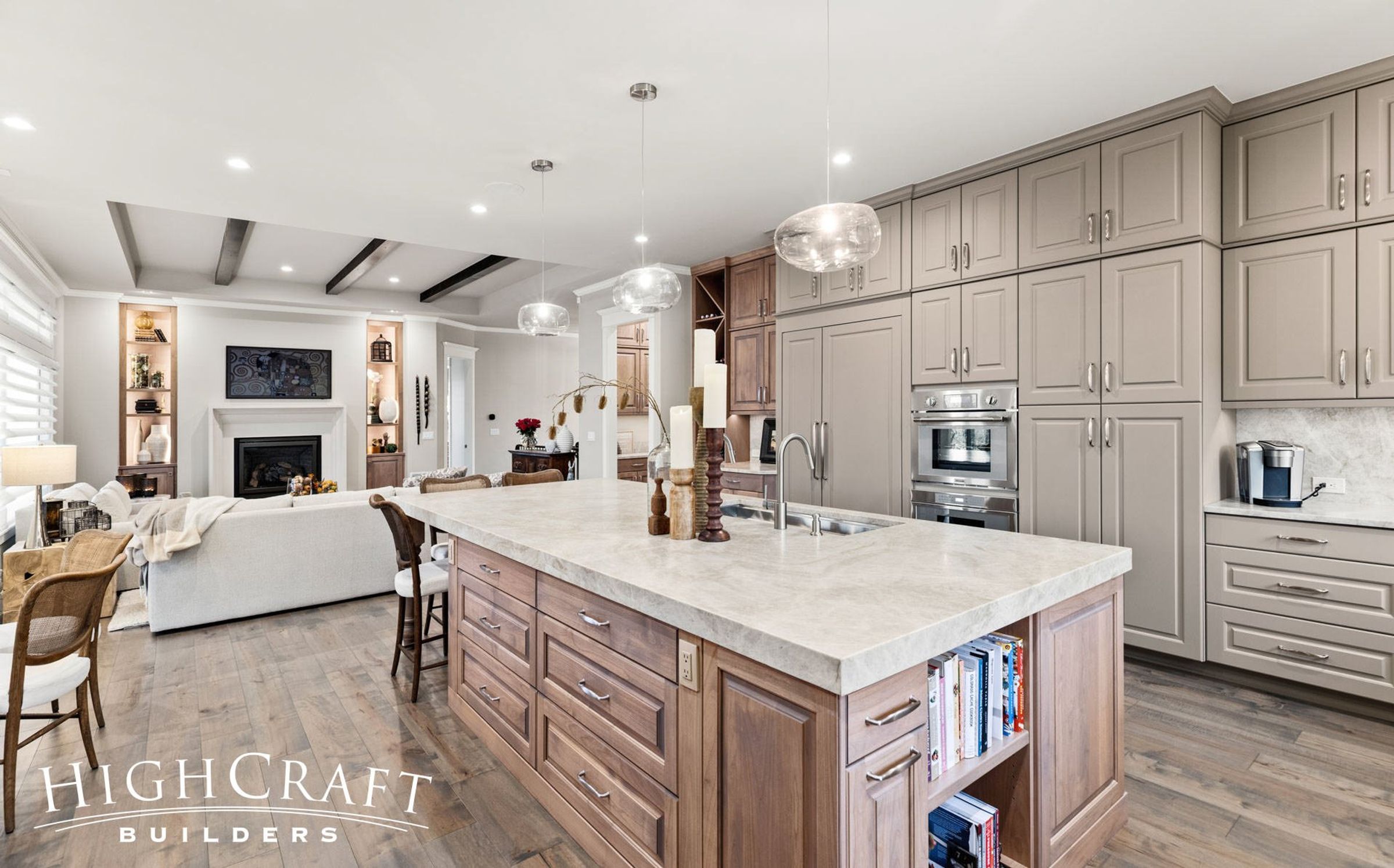 Photo of spacious kitchen remodel with marble island, and light wood-colored custom cabinetry. The color palette is white and light beige with gold hardware accents.