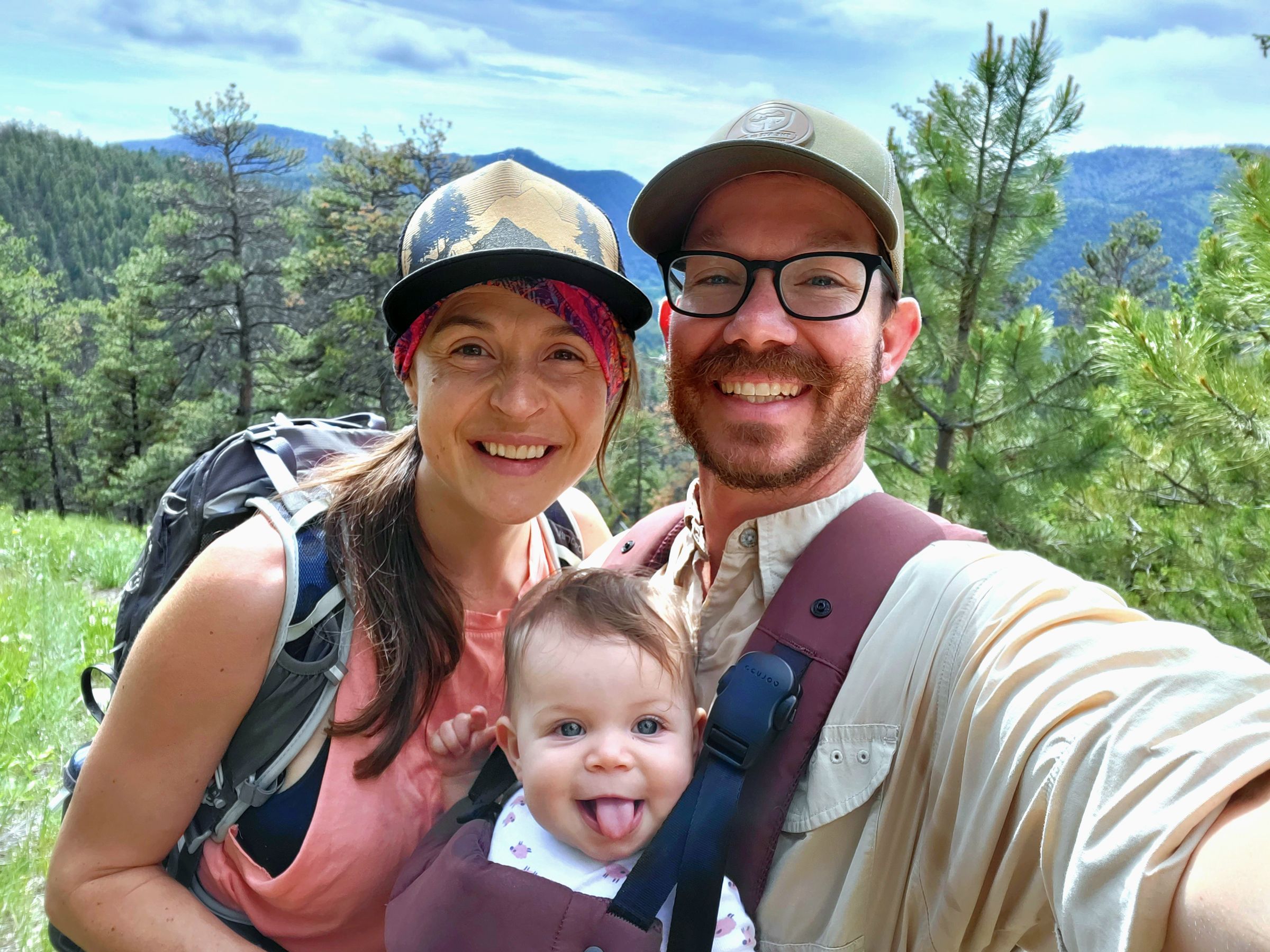 Massey Brooks smiling, in hiking gear with wife and daughter