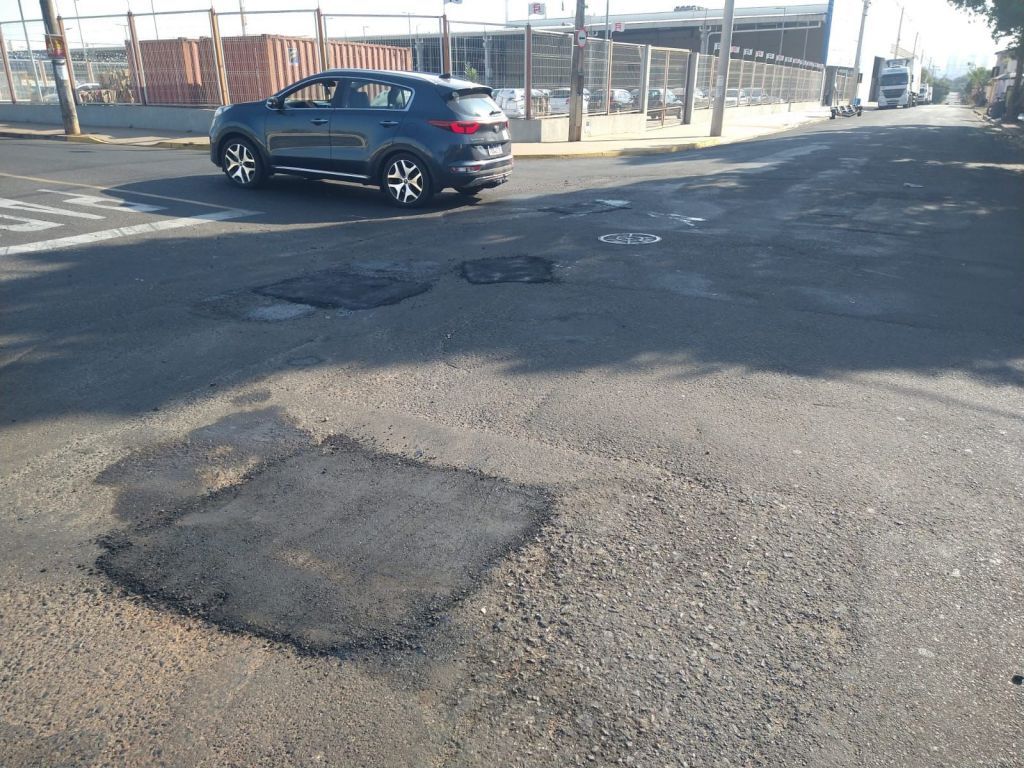 Operários aplicando massa asfáltica em rua de Araçatuba para recuperação viária.