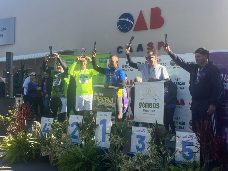 Corredores da OAB Dracena cruzam linha de chegada; celebração esportiva.