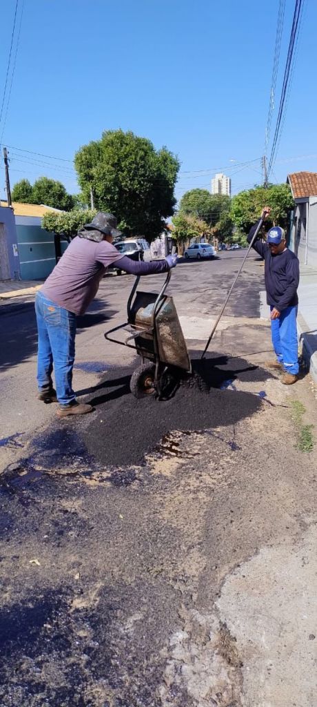 Operário aplica massa asfáltica em buraco de rua em Araçatuba.