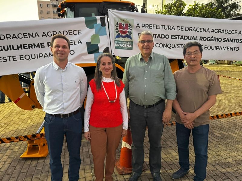 Prefeita Geni Lobo e autoridades ao lado de retroescavadeira em Dracena.