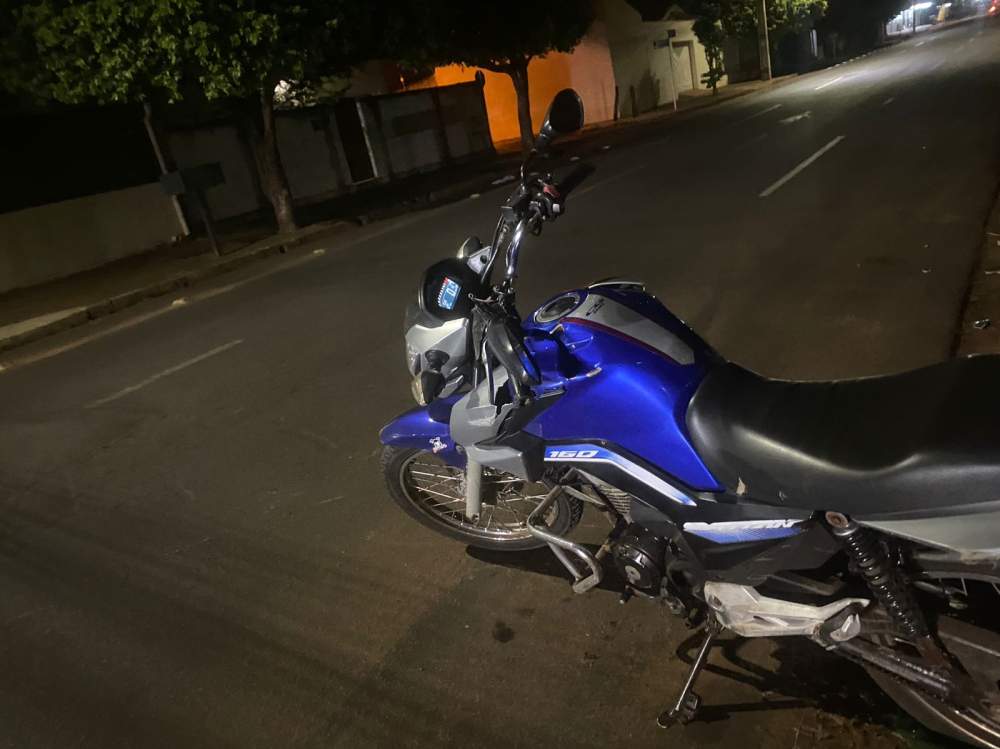 Veículo preto colide com motocicleta ocupada por dois jovens no cruzamento de vias em Três Lagoas; motorista fugiu do local sem prestar socorro.
