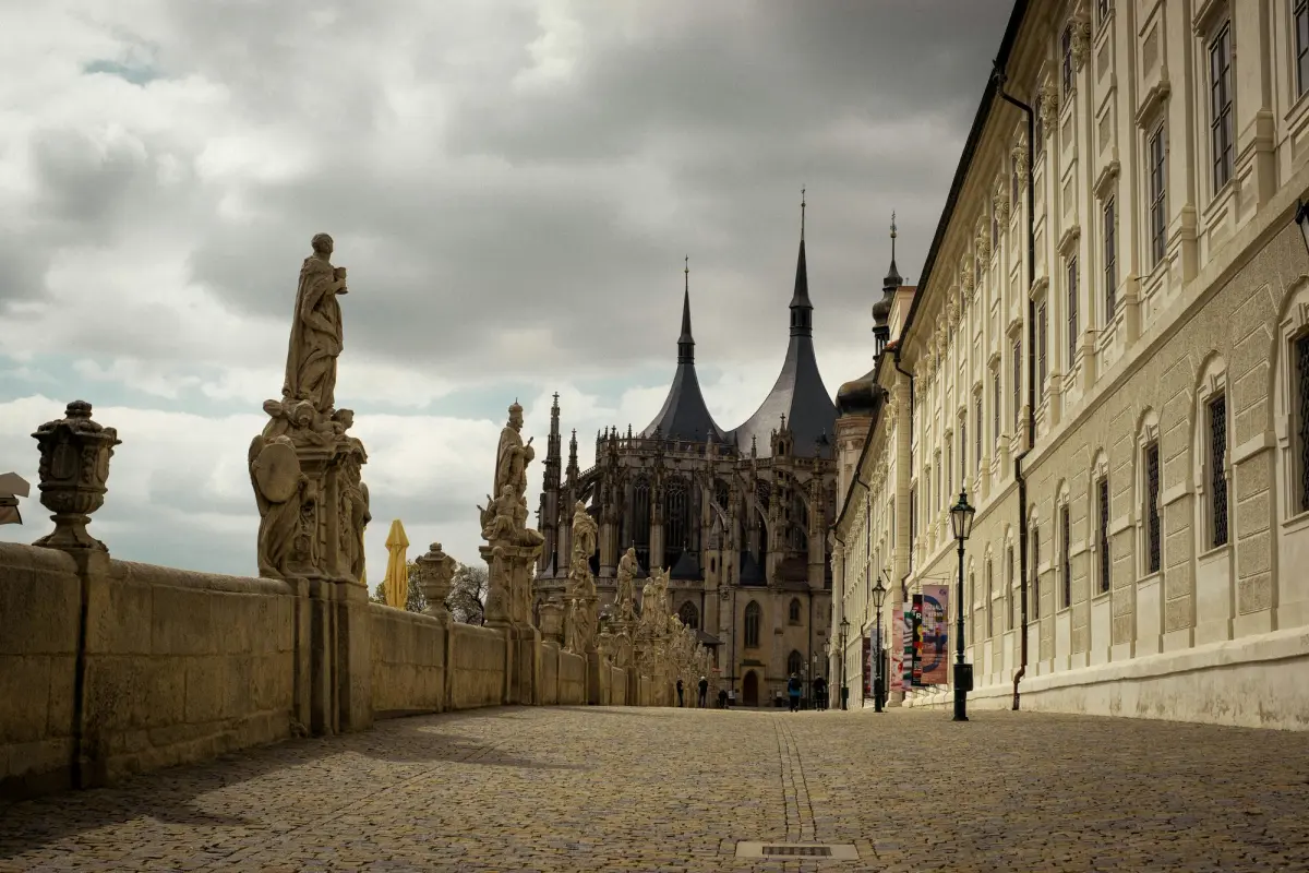 Cobbled street in Kutná Hora's historic centre with medieval facades and St Barbara's Cathedral in the background