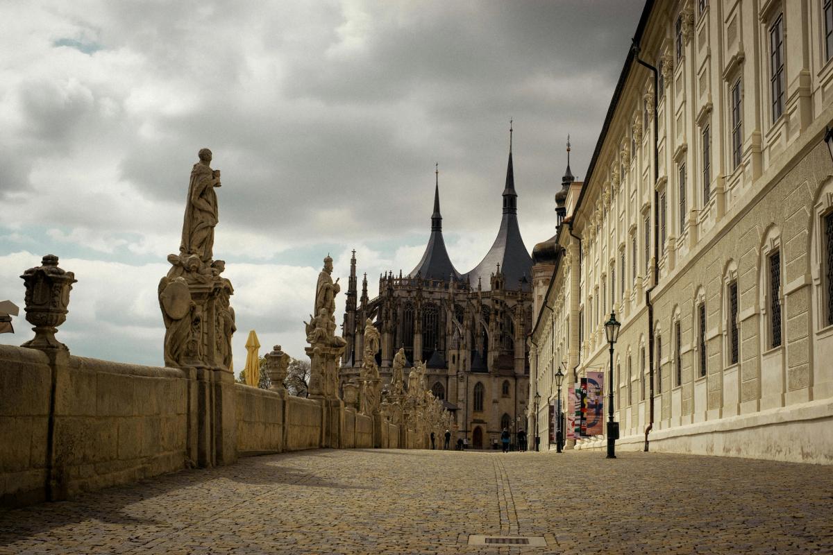 Cobbled street in Kutná Hora's historic centre with medieval facades and St Barbara's Cathedral in the background