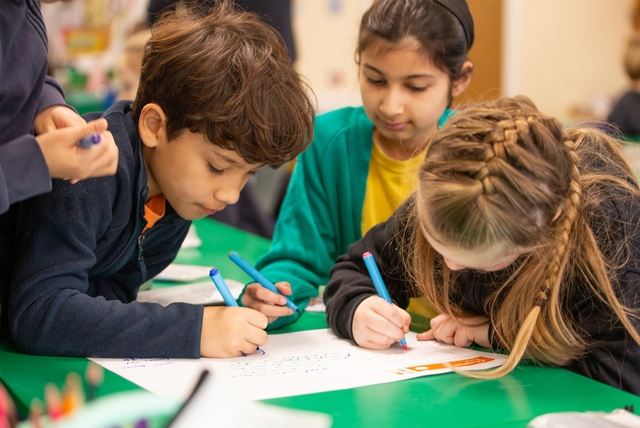 Three students working on one paper together.