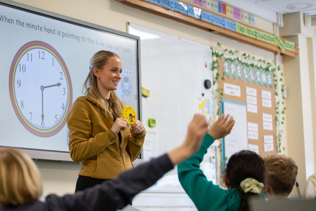 Teacher with a clock in front of a class