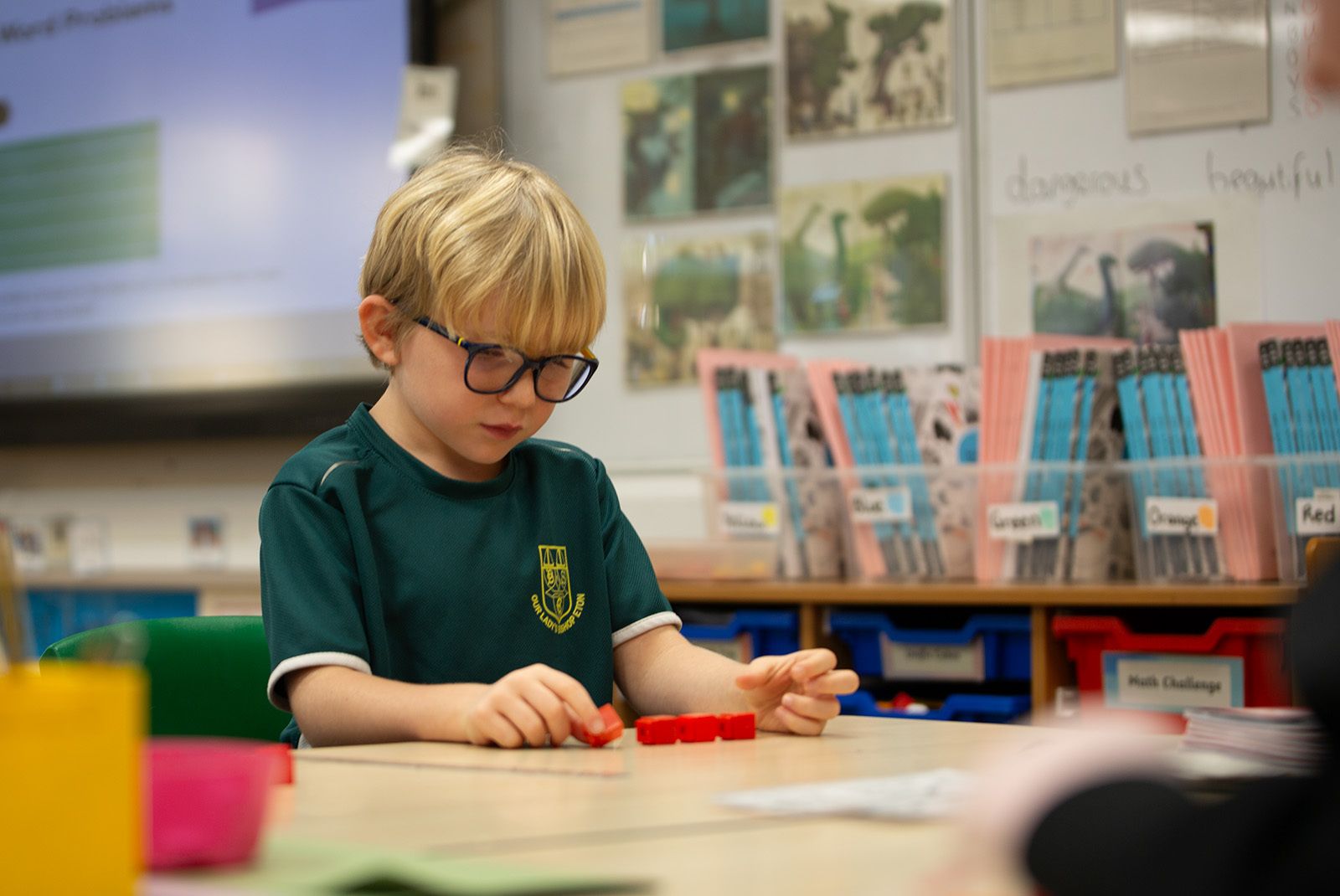A young blonde-haired boy with glasses working with manipulatives.