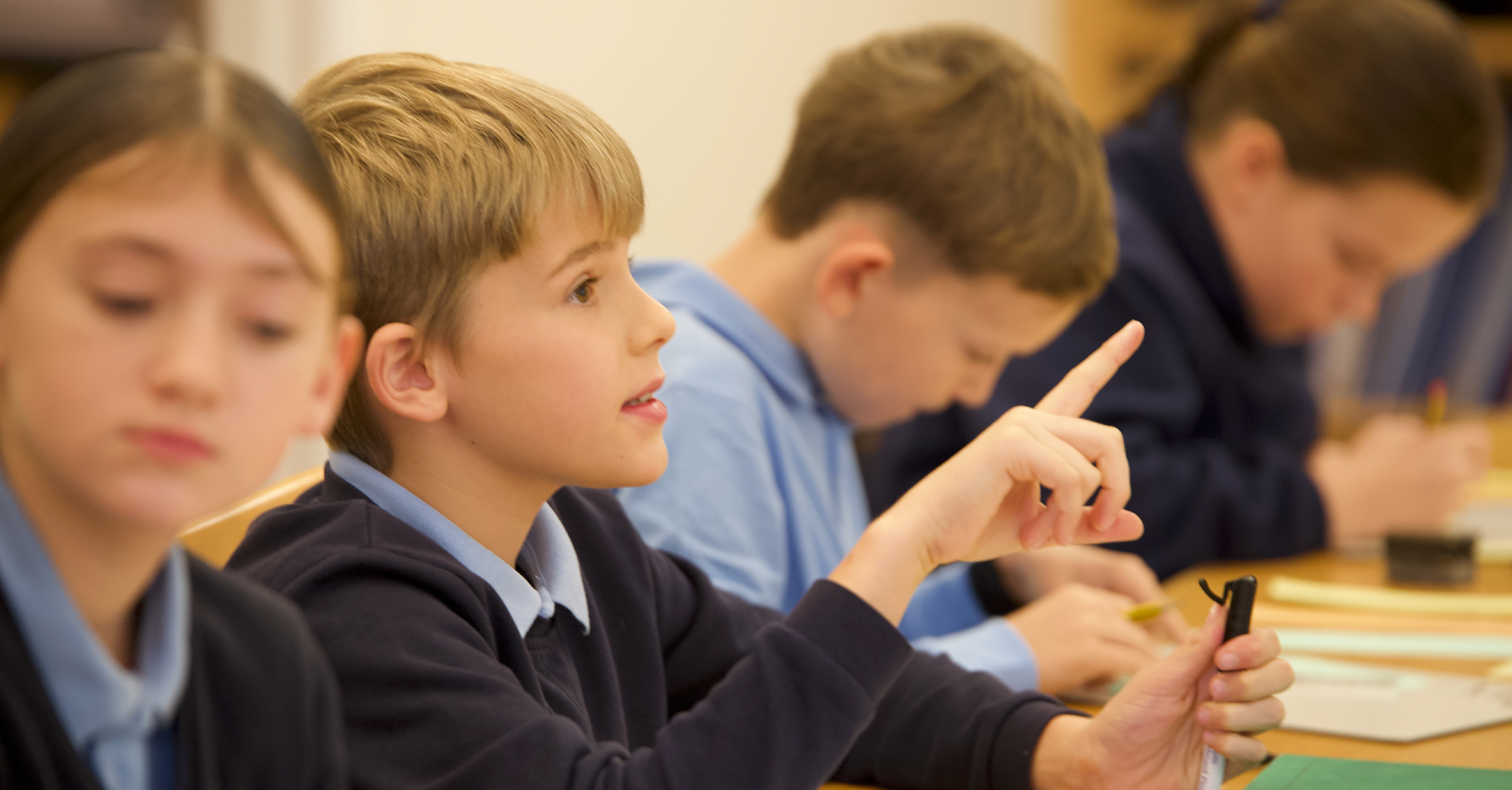 Pupil pointing finger at the front of class to ask a question.