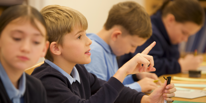 Pupil pointing finger at the front of class to ask a question.